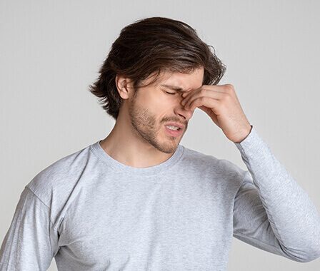 Man Pinching His Nose in Pain