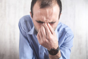 man holding his nose from sinus pressure