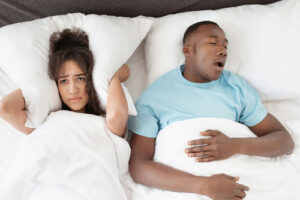 man snoring and woman covering her ears