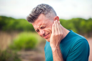 man holding his ear in pain 