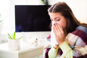 woman using tissue to blow her nose